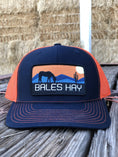Load image into Gallery viewer, This hat is both well-made and comfortable to wear that features the first patch we ever designed! It represents the horses we feed, and the landscape we live in.
